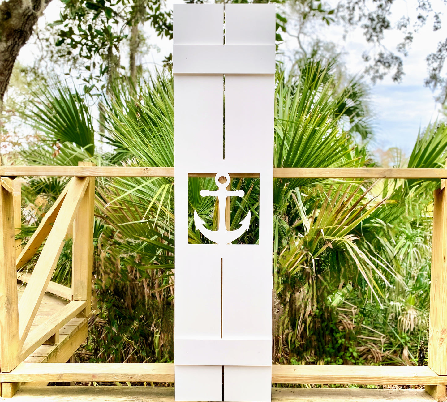 Exterior board and batten style coastal window shutters with nautical anchor cutout. Weatherproof PVC beach house shutters for outdoor decor.