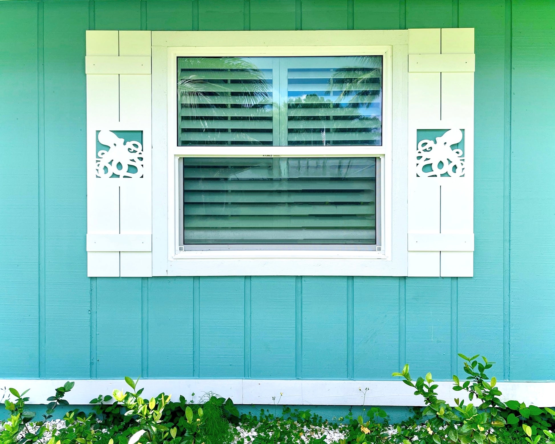 Exterior board and batten style coastal window shutters with ocean octopus cutout. Weatherproof PVC beach house shutters for outdoor decor.